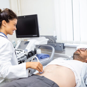 Médica realizando una ecografía abdominal en paciente.